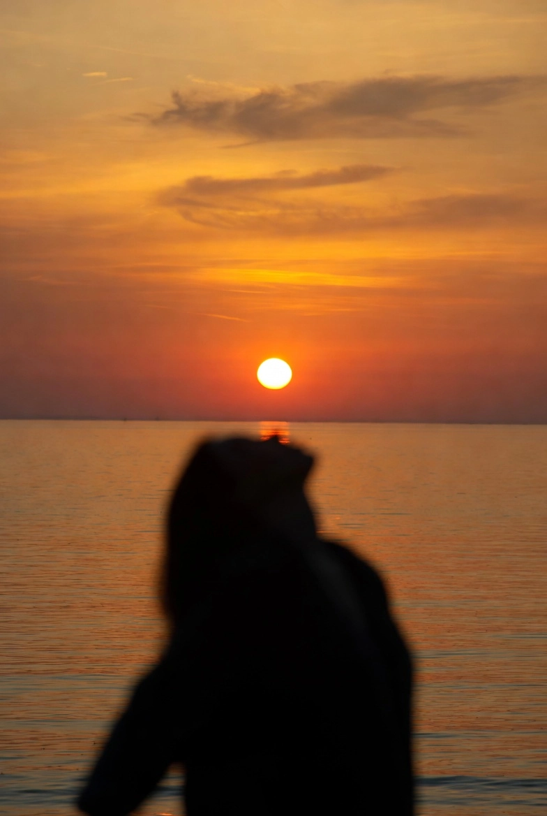 Жінка на фоні заходу сонця навесні під час вечірньої прогулянки