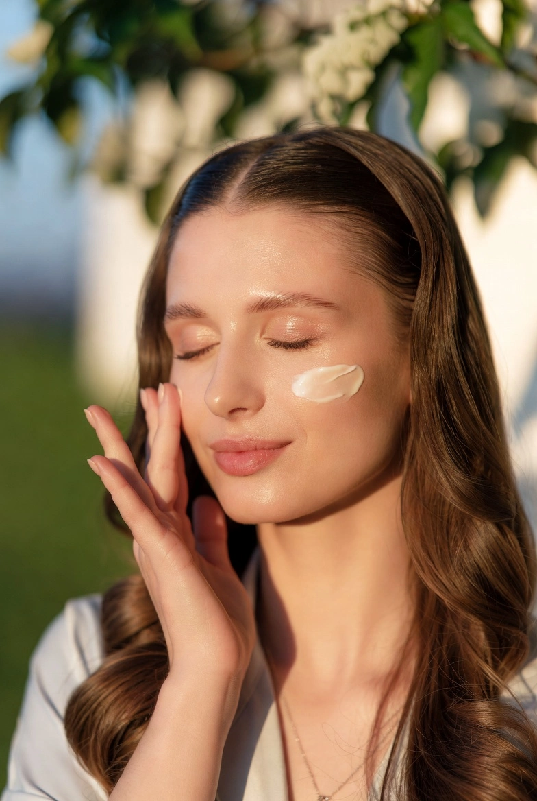 Жінка наносить зволожуючий засіб на шкіру обличчя, щоб уникнути сухість шкіри після зими